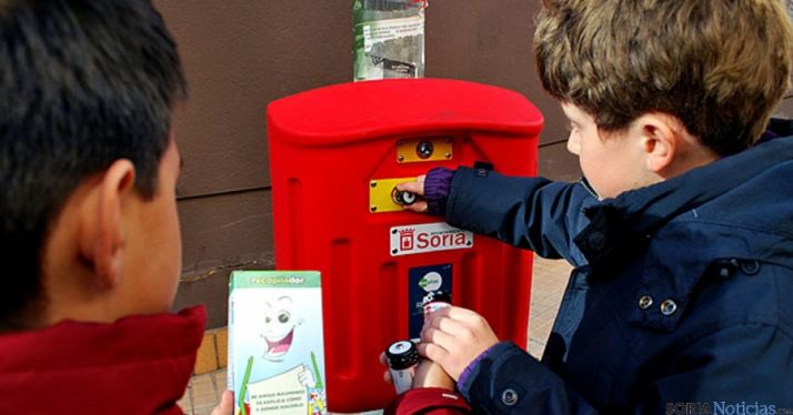 Dos niños depositando pilas en un contenedor. / SN