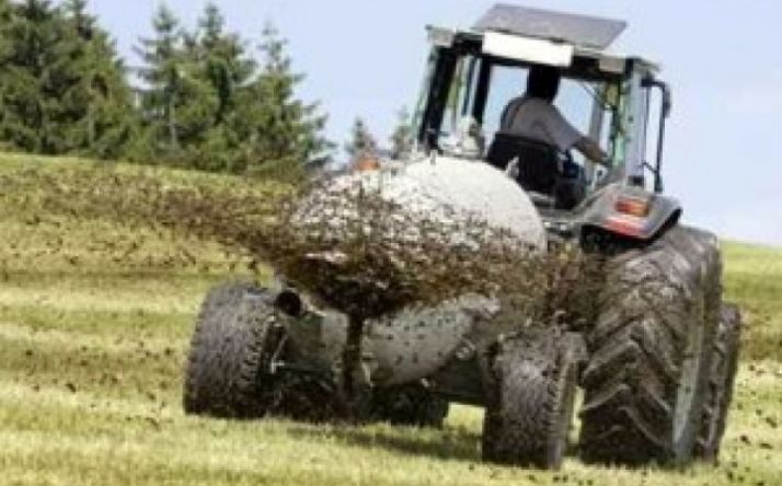 Un tractor esparce purines en un campo. 