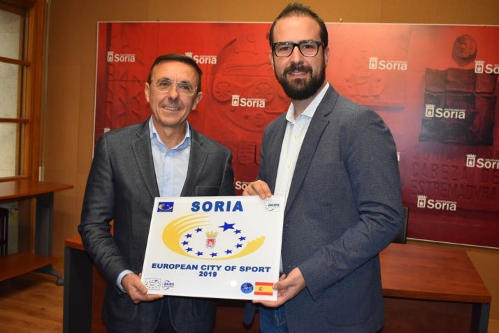 José Hidalgo y Ángel Hernández sujetan una bandera en la que se dibuja Soria, Ciudad Europea del Deporte. Ayuntamiento de Soria