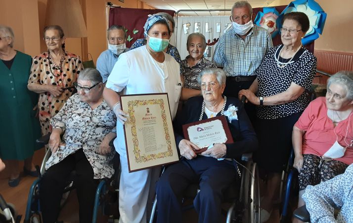La centenaria, con la placa conmemorativa, rodeada de residentes. /Dip.