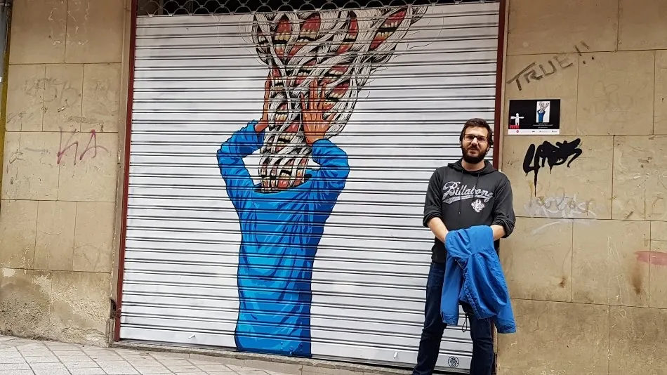 Guillermo Bueno junto a la obra que ha ganado este concurso de arte urbano
