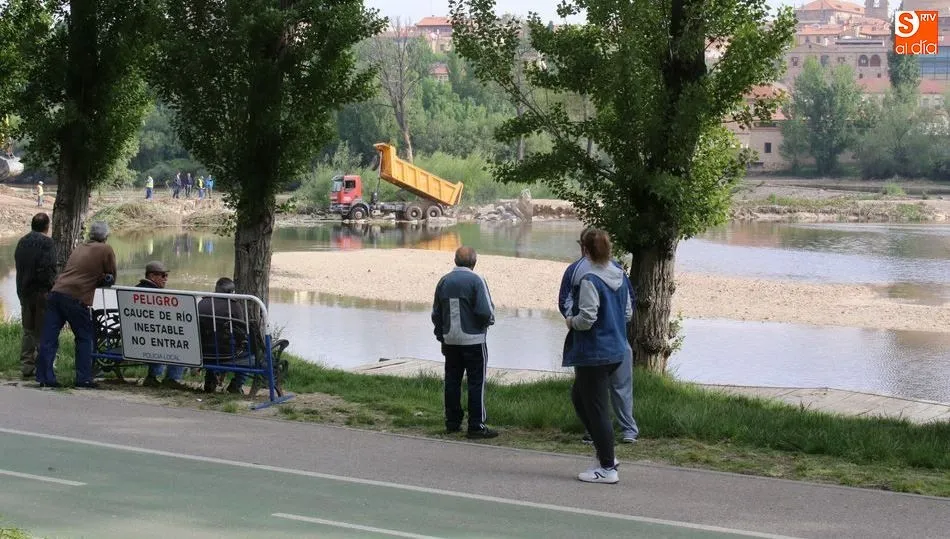 La operación de limpieza con una excavadora en el río llama la atención de los viandantes. Foto de Alberto Martín