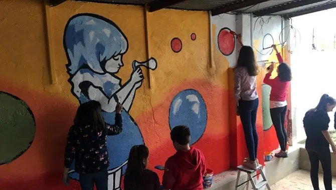 Grandes y pequeños colaboraban en la creación del mural participativo en Rágama