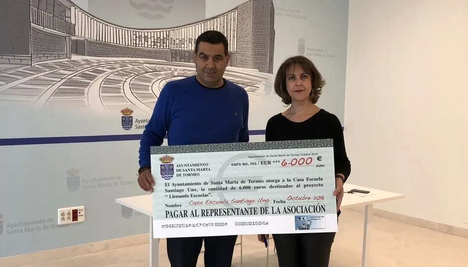 Jesús Garrote, director de la Casa Escuela Santiago Uno, recibe el cheque de manos de la concejala Andrea García