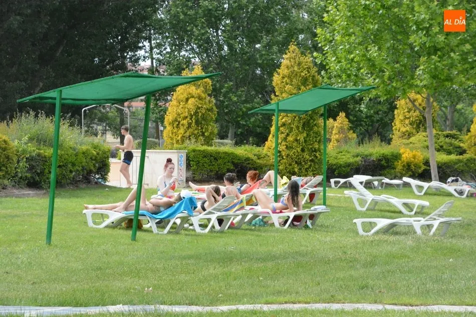 Jóvenes tomando el sol en una piscina.