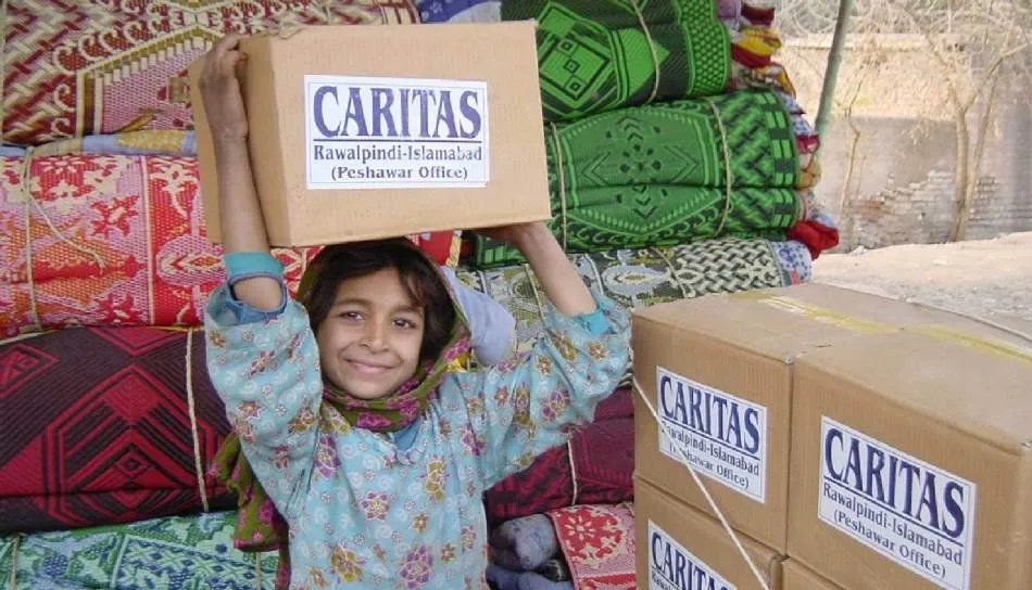 Una niña afgana porta un lote de ayuda alimentaria de Cáritas. Foto Cáritas