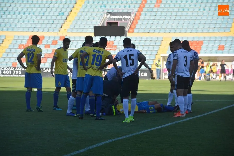 Los jugadores del Salamanca UDS y el Real Unión observan a un compañero tendido en el césped