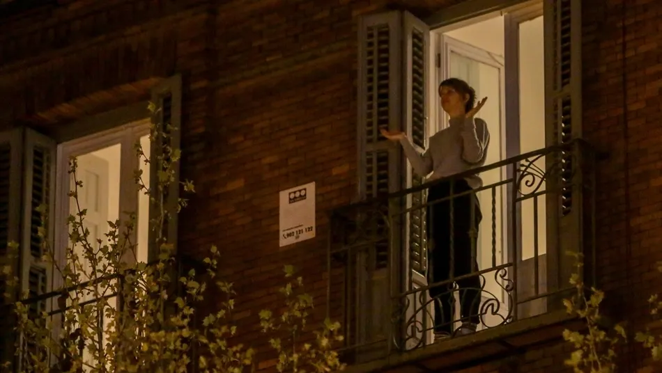Una mujer aplaude desde el balcón de su casa