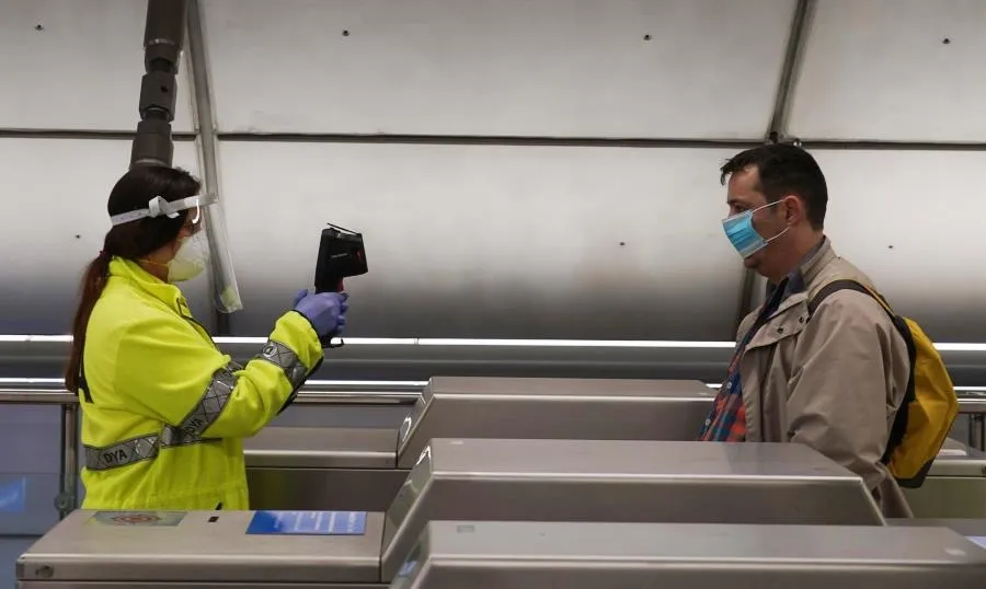 Una voluntaria de la DYA toma la temperatura con una pistola a un viajero en la estación de metro de Otxarkoaga, en Bilbao. Foto H. Bilbao - EP