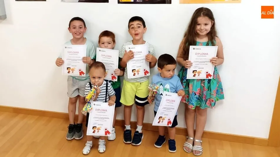 Un grupo de niñas y niños muestran con orgullo sus diplomas