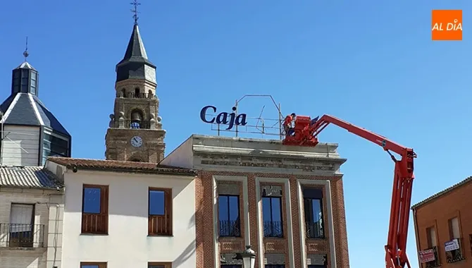 Una grúa y varios operarios retiraban el letrero luminoso de Caja Duero