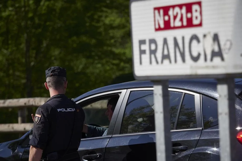 Un cartel señala la dirección a Francia mientras un policía interroga a un conductor en un control en la frontera navarro-francesa. - Eduardo Sanz - Europa Press - Archivo