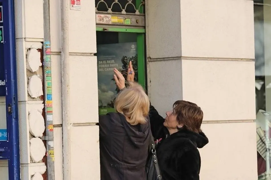 Dos mujeres bajan la trapa de un negocio