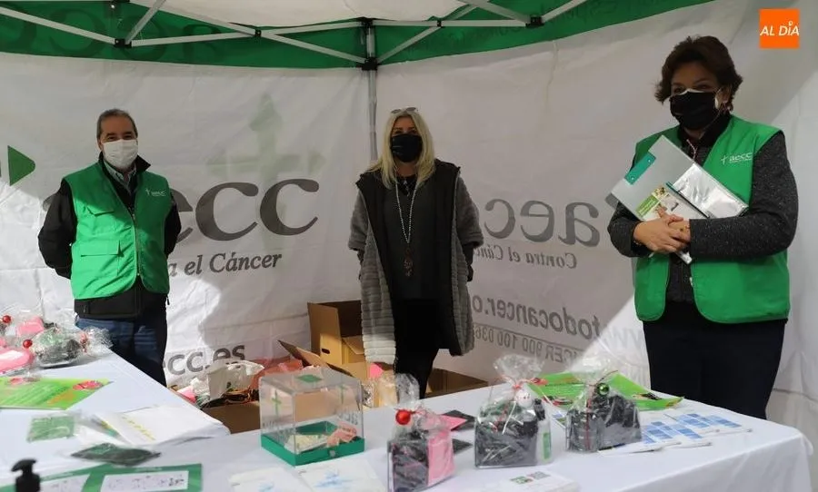 Inmaculada Rodríguez, presidenta provincial de la AECC en Salamanca, en el centro, junto a dos voluntarios en la carpa de los Bandos. Foto de Lydia González