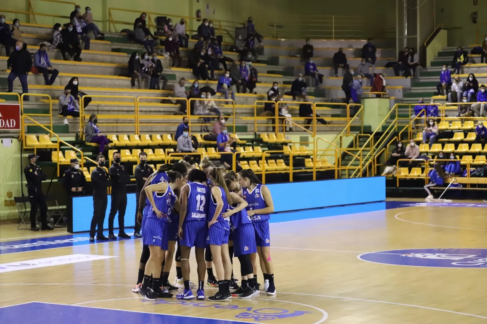 Piña de las jugadoras del Avenida con el público en las gradas como fondo / Lydia González
