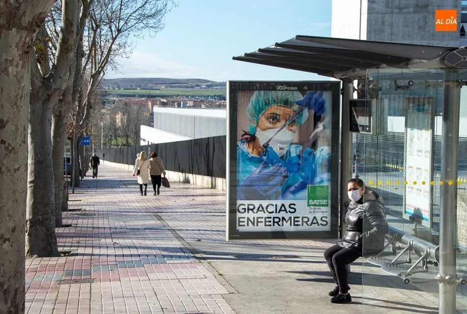 Una mujer con mascarilla en una parada del autobús