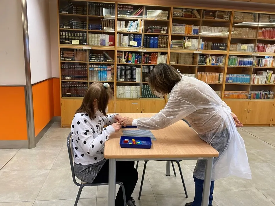 Educadora mostrando a una alumna las piezas de LEGO Braille - ONCE