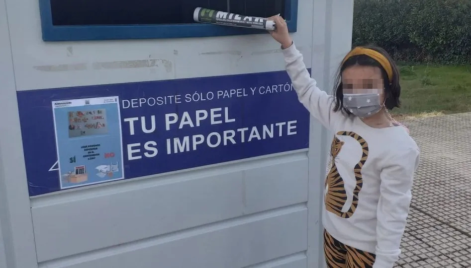 Uno de los contenedores donde se han pegado carteles con frases de niñas y niños animando al reciclaje