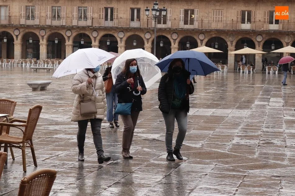 Unos peatones se protegen de la lluvia en la Plaza Mayor - Archivo