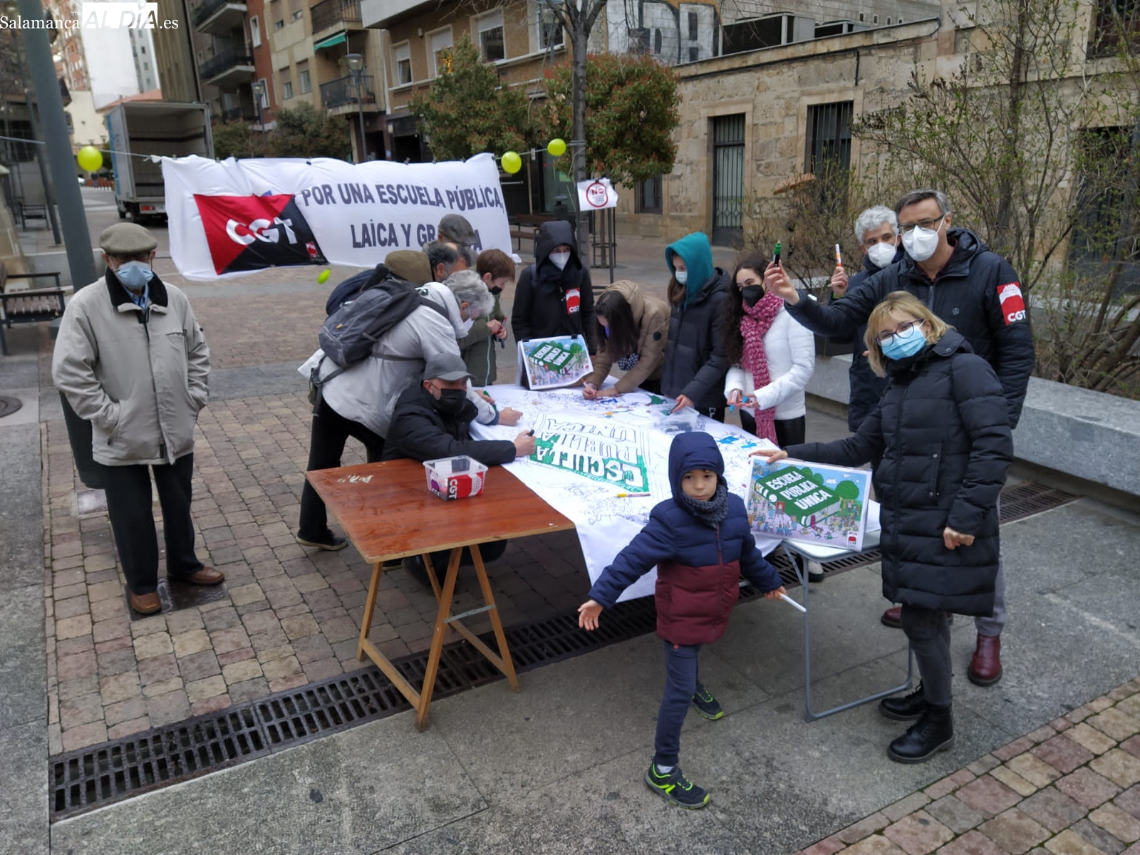 Niños y padres crean una colorida pancarta en favor de la escuela pública