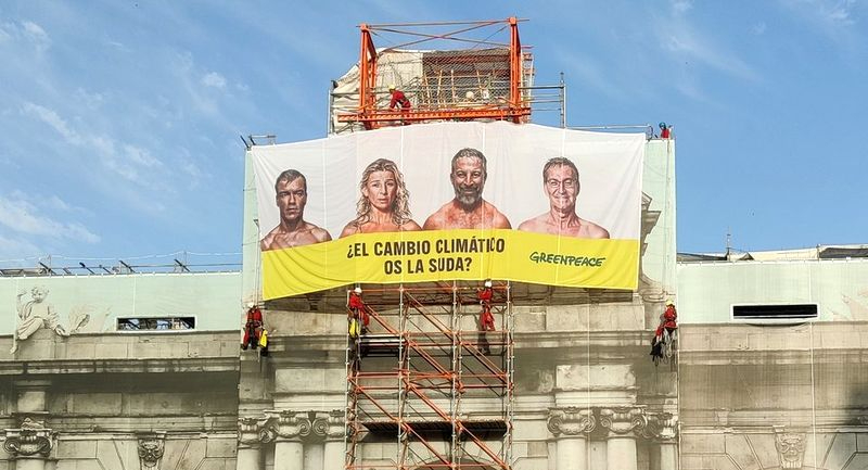¿El cambio climático os la suda?, Greenpeace cuelga una lona en la Puerta de Alcalá con la cara de los candidatos
