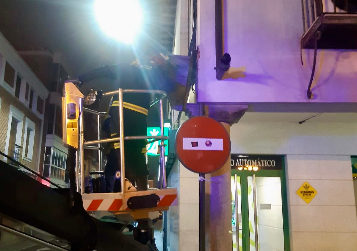 Los bomberos retiran una pesada pieza de madera en la Plaza de España, que amenazaba con caer a la calle