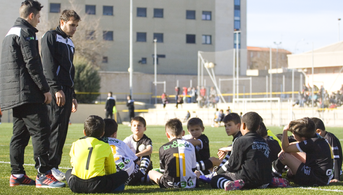 Dos preparadores de Unionistas charlan con unos niños