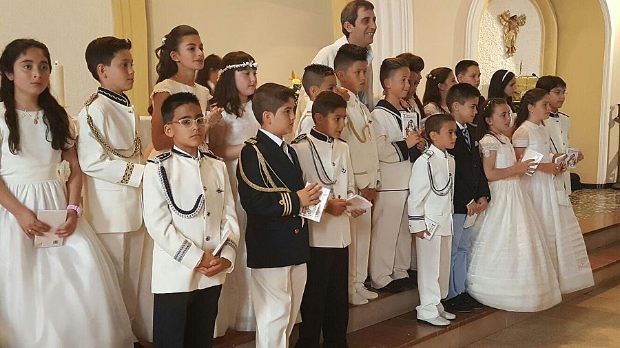 Sacerdote y niños tras la celebración de la Primera Comunión