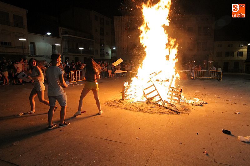 Unos jóvenes hacen sus aportaciones a la hoguera en la plaza Mayor de Guijuelo.