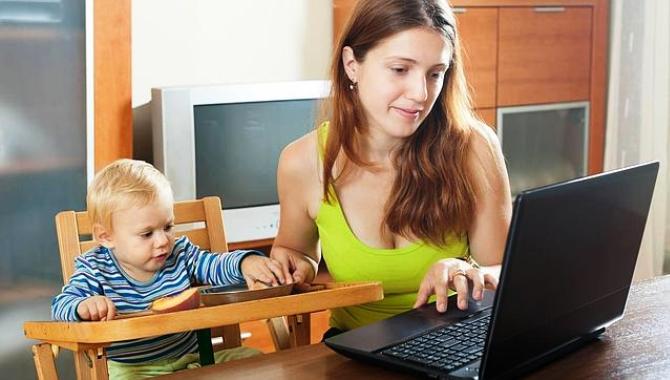 Una mujer maneja un ordenador en compañía de su hijo pequeño