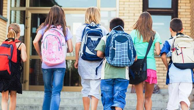 Alumnos portando sus mochilas a la entrada del colegio