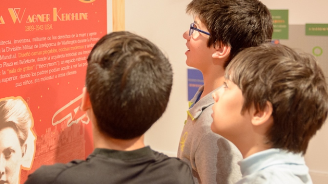 Unos escolares se fijan en uno de los carteles expuestos