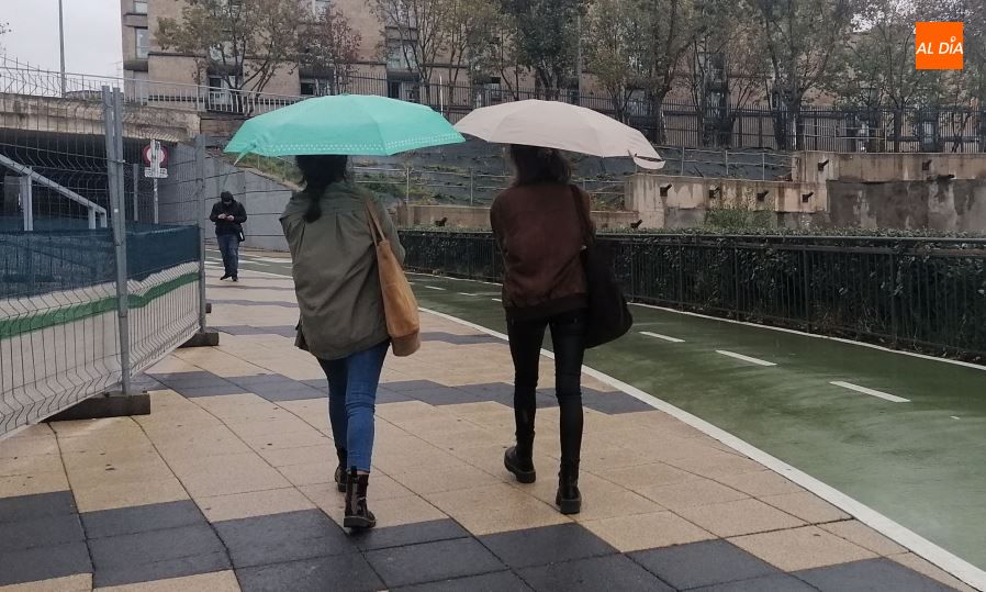 Dos jóvenes pasean bajo la lluvia cerca del Clínico. Foto de Lydia González