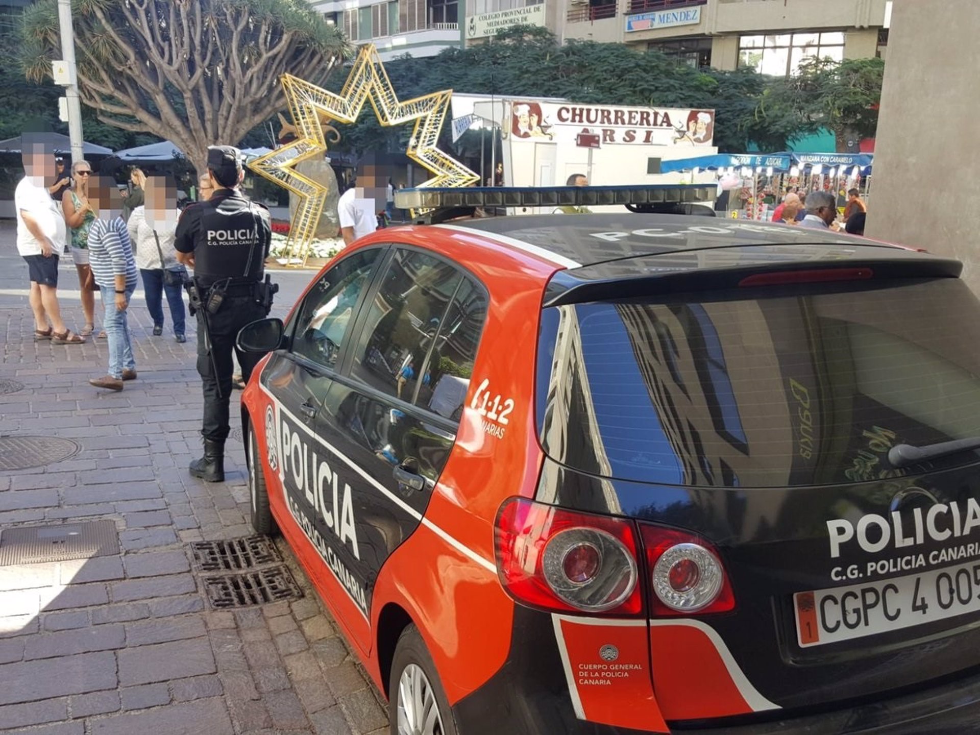 Agente de la Policía Canaria junto a un coche patrulla. EP