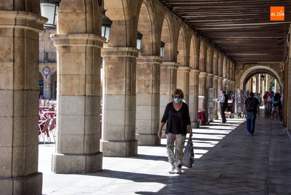 Una mujer con mascarilla caminando por los soportales de la Plaza Mayor