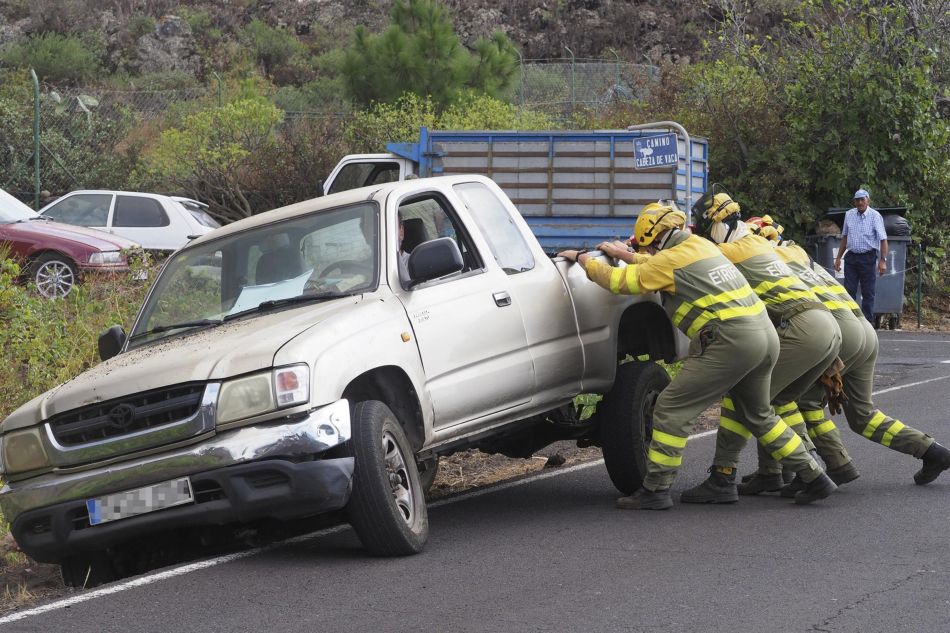 Bomberos ayudan a reincorporar un vehículo a la carretera tras la erupción del volcán de Cumbre Vieja - Europa Press