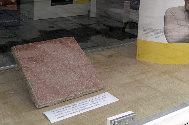 El establecimiento de telefonía que sufría un robo durante la madrugada del viernes muestra en su escaparate la baldosa utilizada para el golpe
