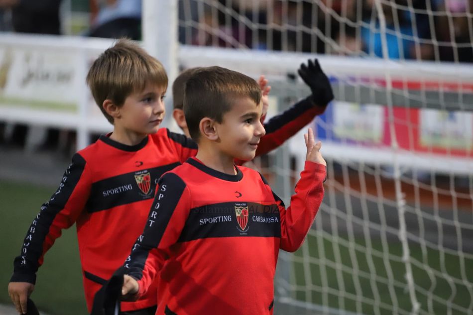 Dos niños saludan a la grada / Lydia González