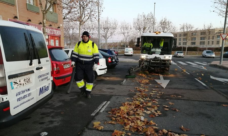 Un operario con sopladora y otro con barredora de calzada recogiendo hojas en Salamanca